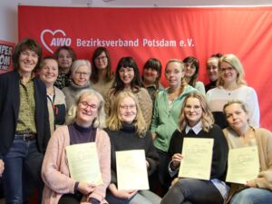 Gruppenbild: 15 Frauen, die lächeln. Vorn sitzen 4 Frauen und halten Ihre AWO Zertifikate vor sich. Die anderen Frauen stehen hinter ihnen.