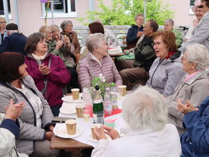 Ältere Menschen an Tischen, leere Teller, leere Kaffeebecher. Sie klatschen der Aufführung.
