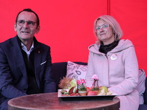 Landrat Marko Köhler und AWO Vorständin Jane Baneth sitzen auf einem Sofa vor einer roten Wand und schauen in unterschiedliche Blickrichtungen.