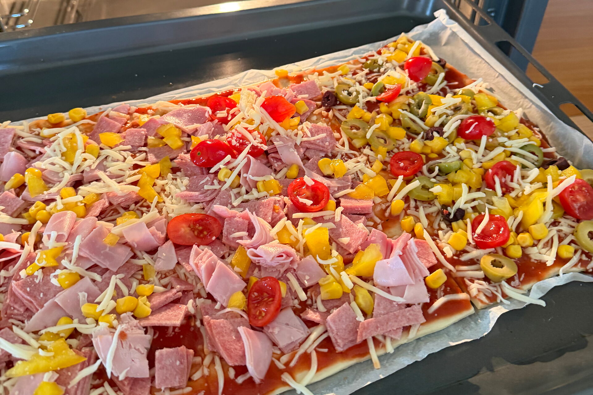 Großes Pizzablech. Mit selbstgemachter Pizza beim reinschieben in den Ofen.