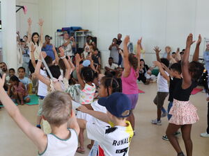 Große Halle. Kinder tanzen etwas einstudiertes vor.