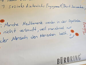Flipchart Papier auf dem unten steht: "Manche Medikamente werden in der Apotheke nicht verkauft, weil manchmal nur der Mensch den Menschen heilt."