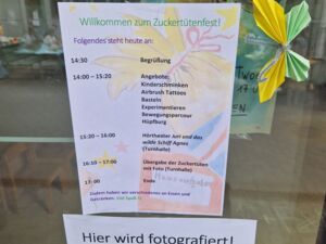 Eine Scheibe an der ein Zettel mit das Programm Tagesablauf hängt. Und ein Hinweis Zettel das fotografiert wird.