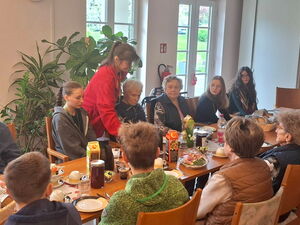 Schüler mit Senioren am Frühstückstisch.