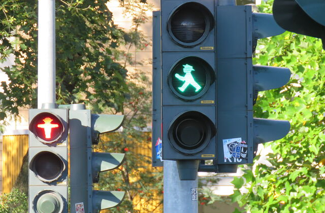2 Fußgängerampeln, die hintere auf rot, die fordere auf grün. Ampelmännchen.