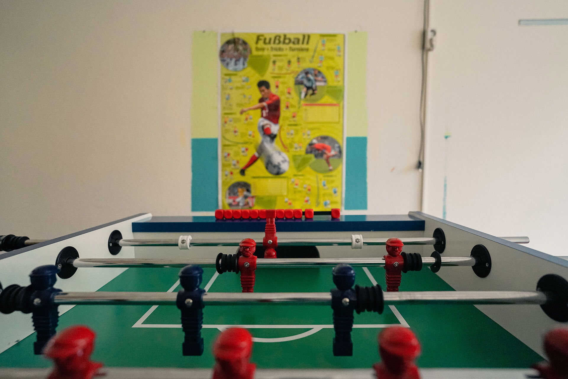 Tischkicker und ein Fußball-Plakat an der Wand.