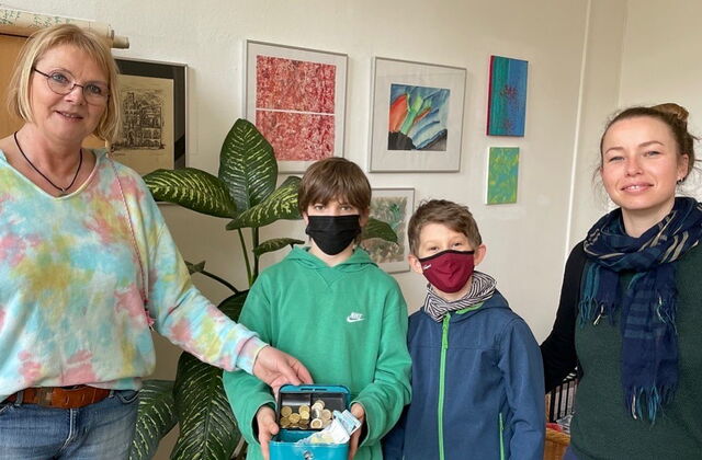 Eine Frau und drei Kinder halten eine Geldkassette nach oben