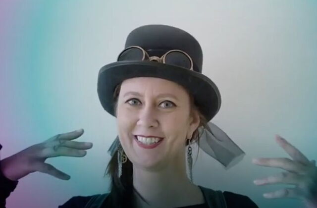 Frau mit im Steampunk Style. Kopf und, Hals und Hände sind sichtbar. Sie trägt Steampunk Hut und Ohrringe. Sie ist geschminkt.