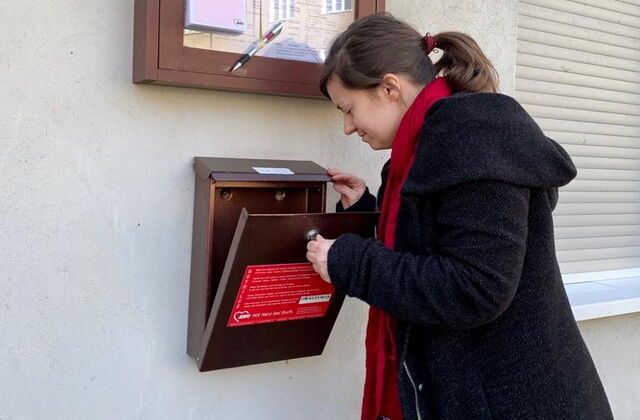 Eine Frau schaut in einen Briefkasten