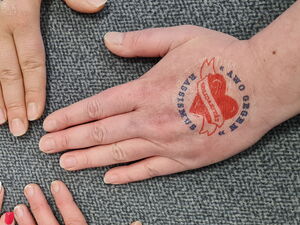 5 Hände von verschiedenen Menschen im Kreis Fin, Auf den Händen sind Stempel: AWO GEGEN RASSISMUS Herz mit Schärpe | AWO GEGEN RASSISMUS MUTIG in der Mitte.