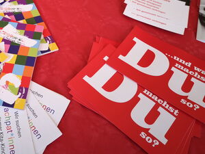 AWO Flyer, Info-Material und Kugelschreiber auf einer roten Tischdecke.