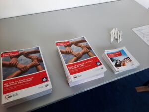 Info-Material und Kugeschreiber auf einem Tisch. Proschüren zum Thema: wie finde ich Arbeit auf dem allgemeinen Arbeitsmarkt?    und     Fragen und Antworten zum Thema Budget für Arbeit