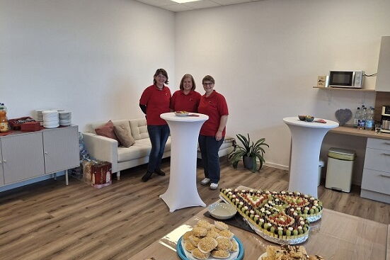 Raum mit Tisch und zwei Stehtischen, auf dem Tisch Kuchen und Obst- und Käsespieße, am Stehtisch stehen 3 Mitarbeiter der Sozialstation Bad Belzig
