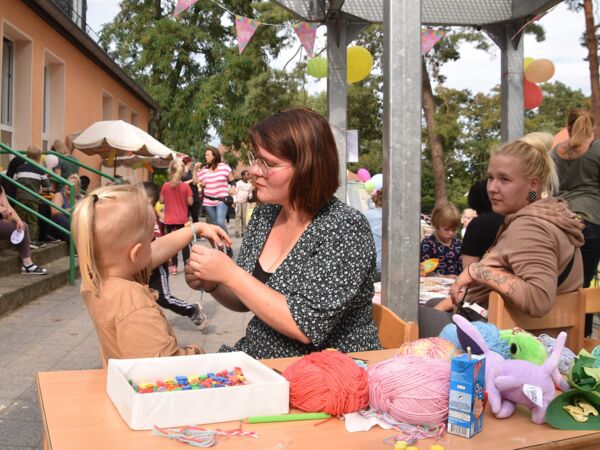 Hier sehen sie Kinder und Erwachsene beim Armbandflechten