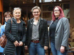 Gruppenfoto im Kino Foyer. 3 Frauen stehen nebeneinander und lächeln in die Kamera.