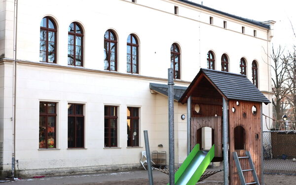Ein kleines Klettergerüst mit Rutsche vor dem Kitagebäude.