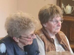 2 Seniorinnen sitzen nebeneinander.