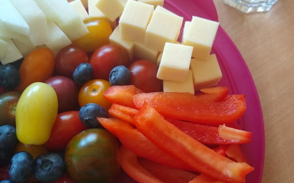 Ein bunter Teller mit Obst, Gemüse und Käsewürfeln
