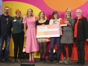 Gruppenbild mit Scheck über 2.000 Euro. Ein Mann und sechs Frauen stehen in einer Reihe, lächeln und 2 der Frauen halten den Preis-Scheck vor sich.