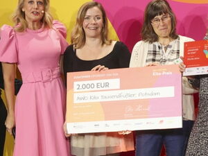 Gruppenbild mit Scheck über 2.000 Euro. Ein Mann und sechs Frauen stehen in einer Reihe, lächeln und 2 der Frauen halten den Preis-Scheck vor sich.