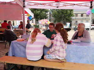 Kinder und Erwachsene sitzen unter einem Pavillon.