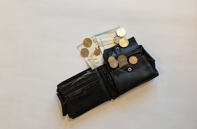Ein aufgeklapptes Herren Portemonnaie. Geld Münzen und Scheine gucken raus.