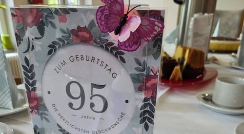 Gedeckter Kaffeetisch. Nahaufnahme einer Karte zum 95. Geburtstag.