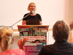 Blonde Frau am Rednerpult.