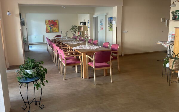 in der Mitte des großen Begegnungsraumes steht eine lange Tafel mit Stühlen daran.