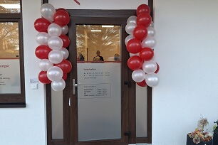 Glastür mit roten und weißen Luftballons rechts und links, über der Tür ein Schild der Sozialstation Bad Belzig mit dem AWO-Logo