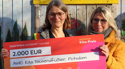 2 Frauen halten einen großen Preis-Scheck in die Kamera und lächeln. Preisgeld: 2.000 Euro.