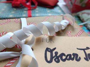 Geschenktüten, eingepackte Geschenke. Im Vordergrund ein Geschenk mit Namensschild: Für Oscar.