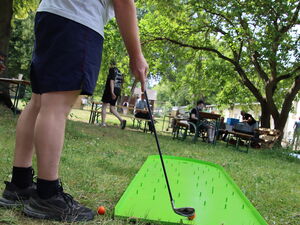 Ein Mann mit rotem Base Cape beim Mini-Golf.