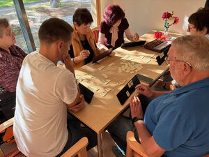 5 Menschen sitzen am Tisch und spielen ein Spiel.