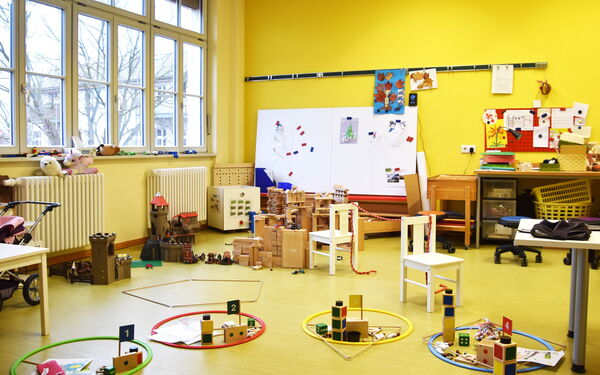 Burgen und Festungen stehen auf dem Fußboden aber auch andere Spielsachen liegen rum. Auf einer Heizung am Fenster sind zwei Kuscheltiere.