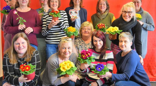 Viele Frauen halten Blumen in Richtung Kamera.