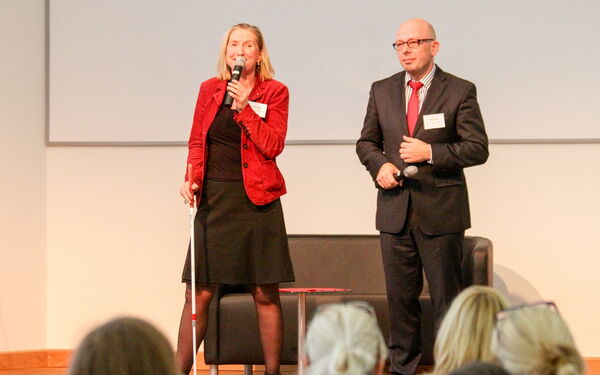 Dörte Maack, Autorin und Moderatorin, steht mit Blindenstock auf der Bühne und moderiert den Vortrag eines Potsdamer Unternehmers an.