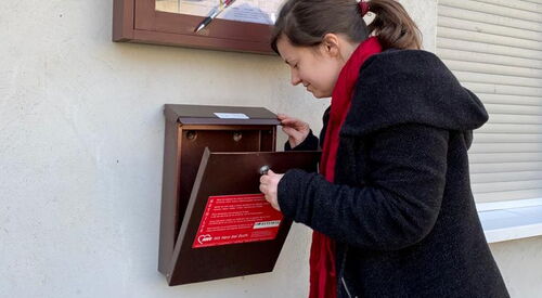Eine Frau schaut in einen Briefkasten