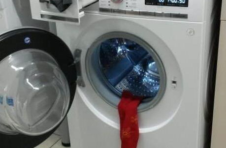 Foto einer Waschmaschine aus der eine Socke hängt
