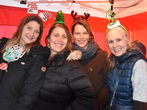 Gruppenbild: 4 Frauen stehen gut gelaunt nebeneinander. Gut gelaunt mit strahlenden Gesichtern. Alle haben Weihnachts-Haarreifen mit lustigen Tannenbäumen, Rentiergeweih auf dem Kopf.