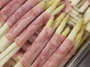 Spargel in Schinken gerollt. Viele Spargelstangen in Großküchen-Behältnis.