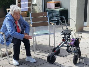 Büchsenwerfen. Seniorin sitzt auf Terrasse und wirft mit einem Säckchen Büchsen um.