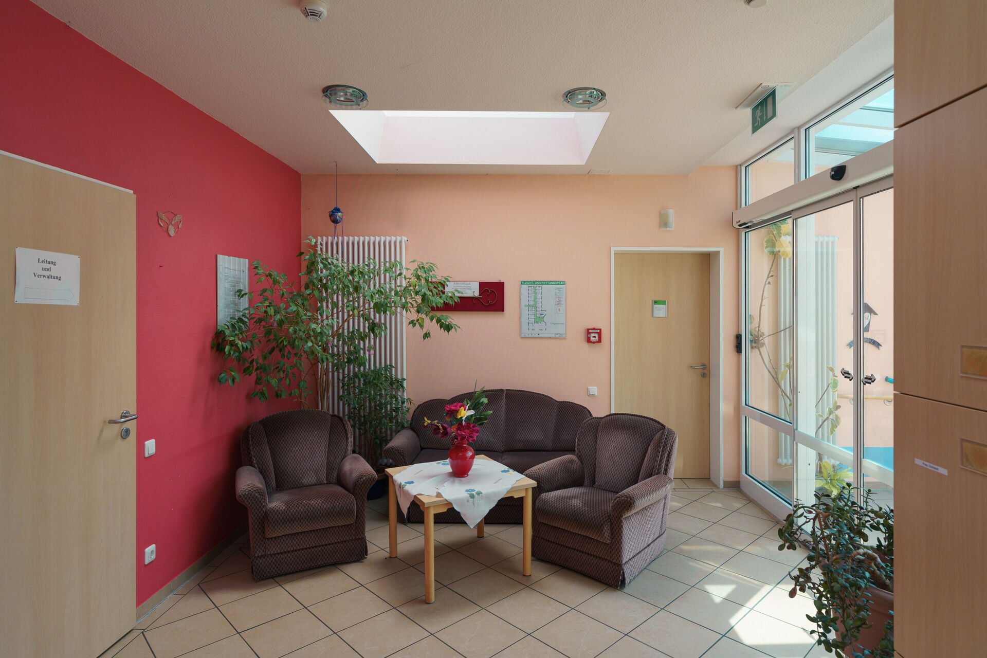 Polstersitzgruppe, Zwei Sessel, ein kleines Sofa dunkelgrau in der Mitte ein Tisch mit Blumenvase.