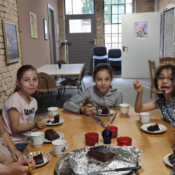 Hier sehen sie Kinder an einer Tafel beim Essen