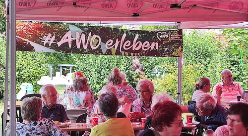 Draußen, Sonne scheint, Kaffeetafeln und größtenteils ältere Menschen die zusammensitzen.
