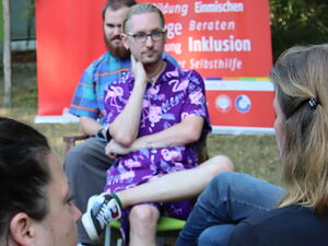 Menschen die in zwei Stuhlkreisen sitzen und miteinander ins Gespräch kommen. Im Hintergrund zwei große AWO Roll-Up Banner