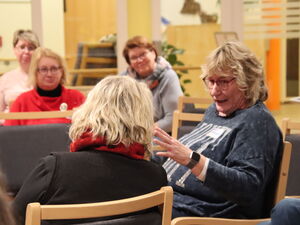 Menschen sitzen in Stuhlkreisen, zwei Frauen im inneren Kreis diskutieren.