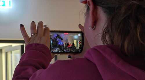 Eine Frau hält ein Smartphone hoch und filmt damit das Kulturprogramm.