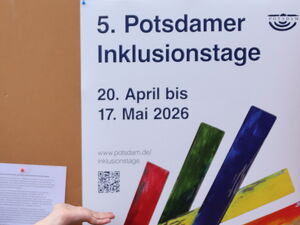 Frau weißt auf ein Plakat der 5. Potsdamer Inklusionstage.