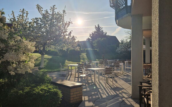 Sonnenüberflutete Terrasse Mit Stühlen und Tischen.